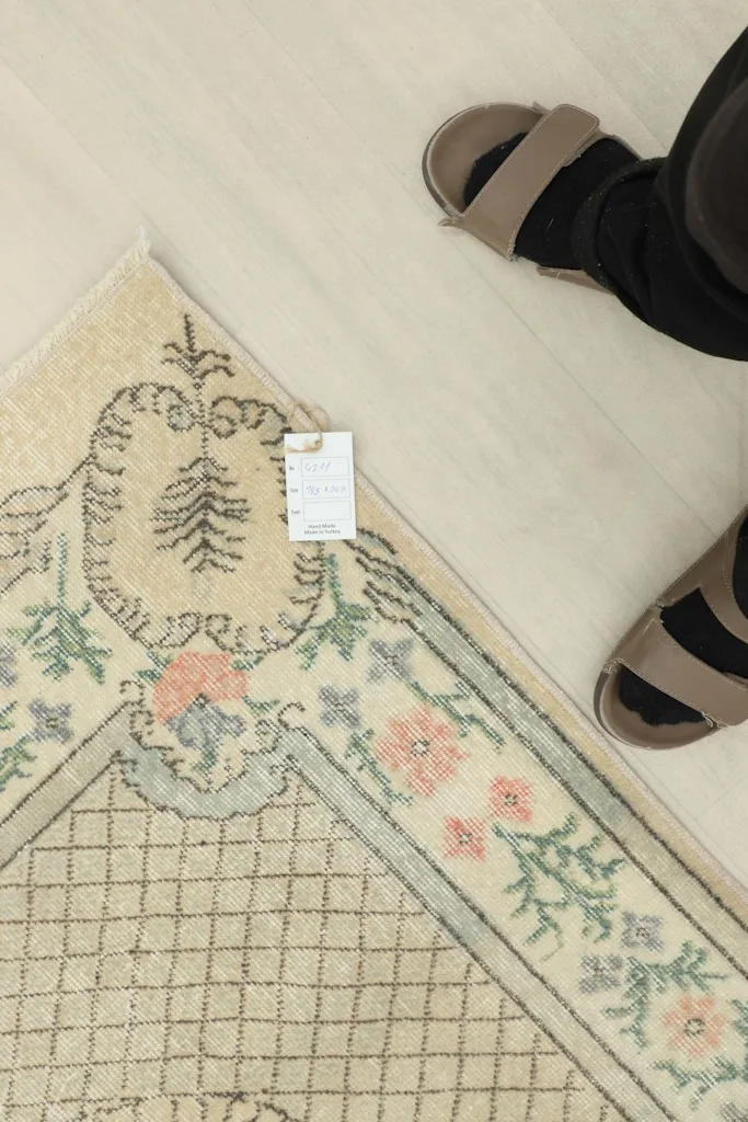 Overhead view of a corner of the rug next to feet, showing scale and a small tag.