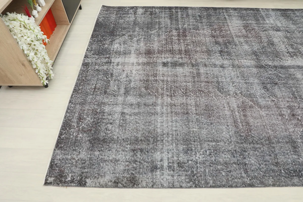 Corner view of the charcoal and gray rug, showing its faded appearance
