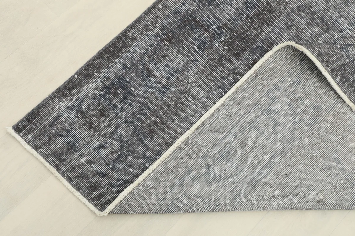 Corner of the rug folded back, showing the cotton foundation