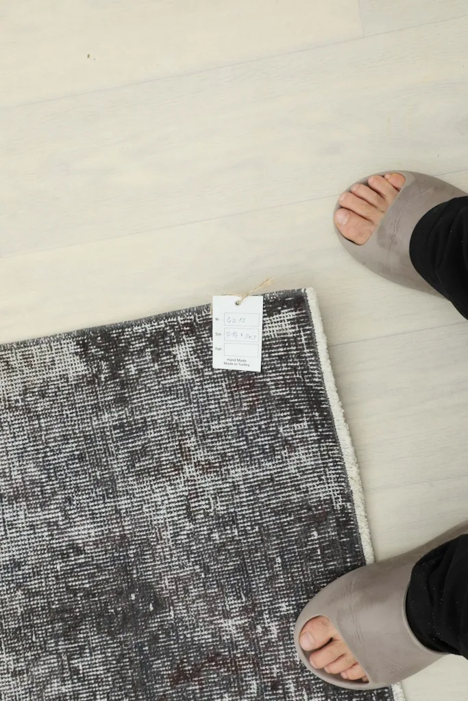 Overhead view of a corner of the rug with a size tag and feet for scale