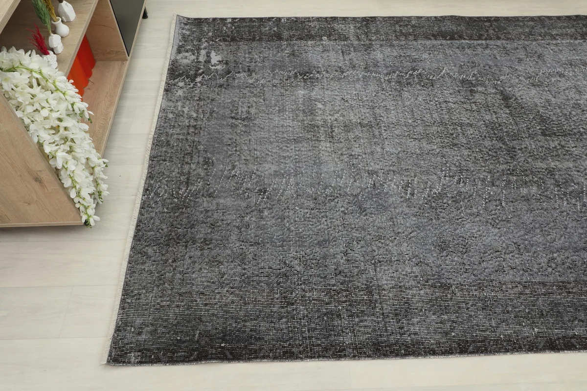 Another angle shot of the charcoal vintage rug, showing the distressed surface and color variation.