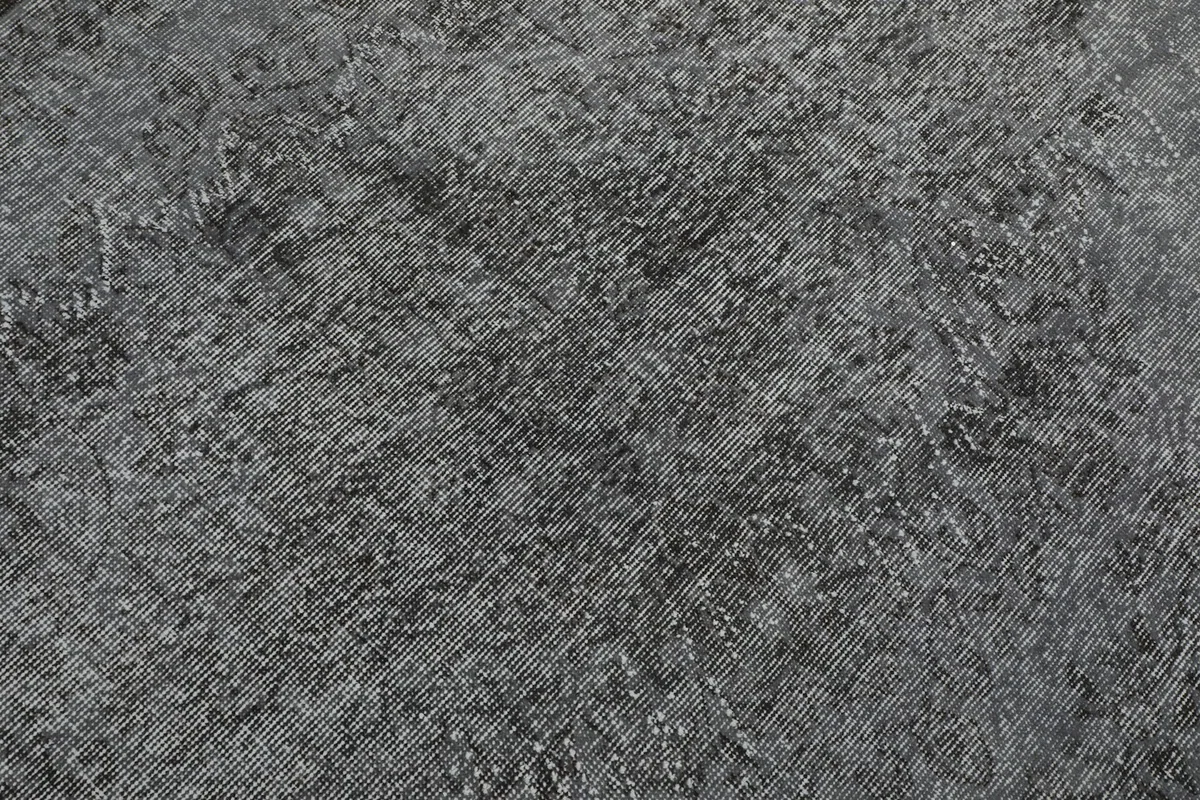 Detailed view of the rug's surface, showing the hand-knotted wool pile and distressed finish.