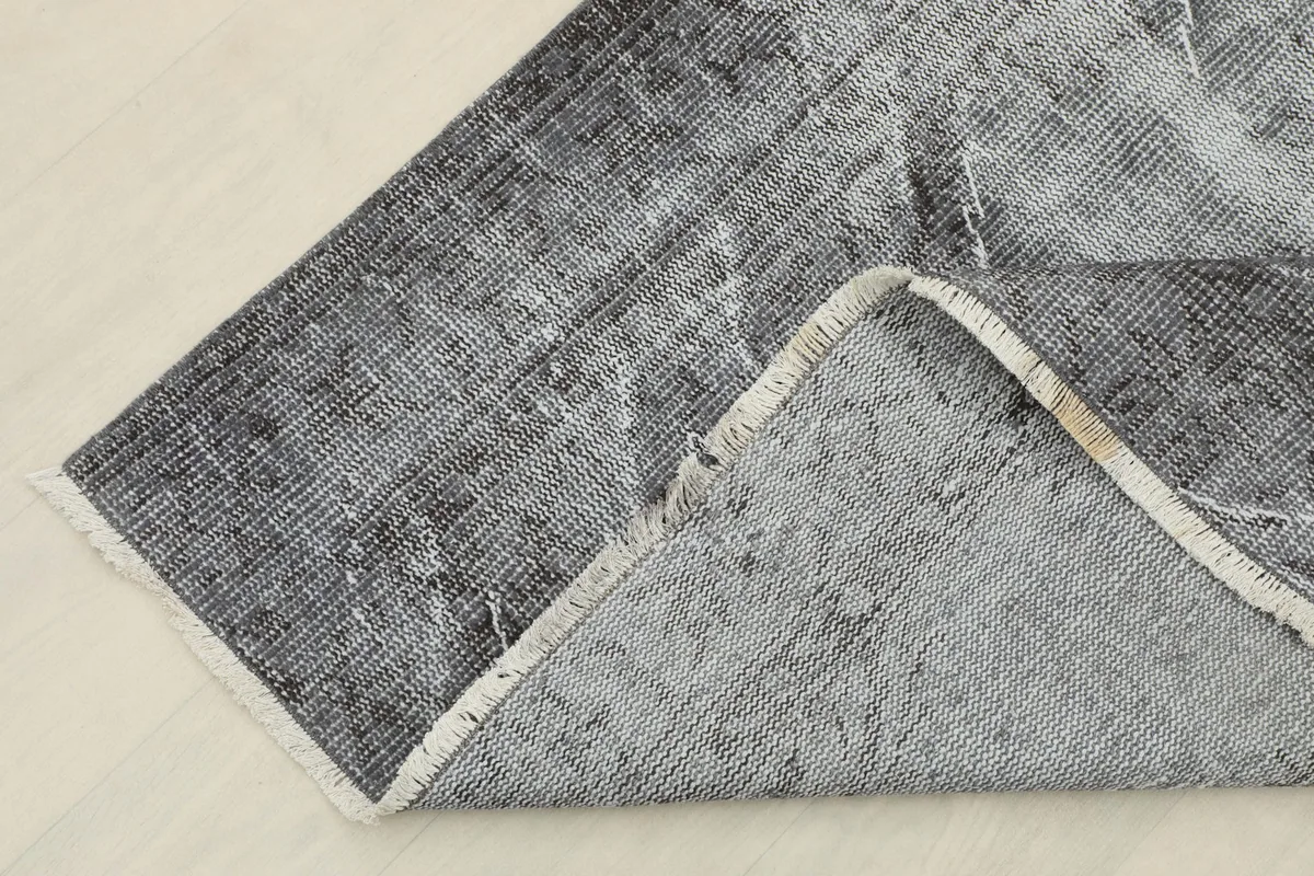 Corner of the rug folded back to show the cotton foundation and reverse side