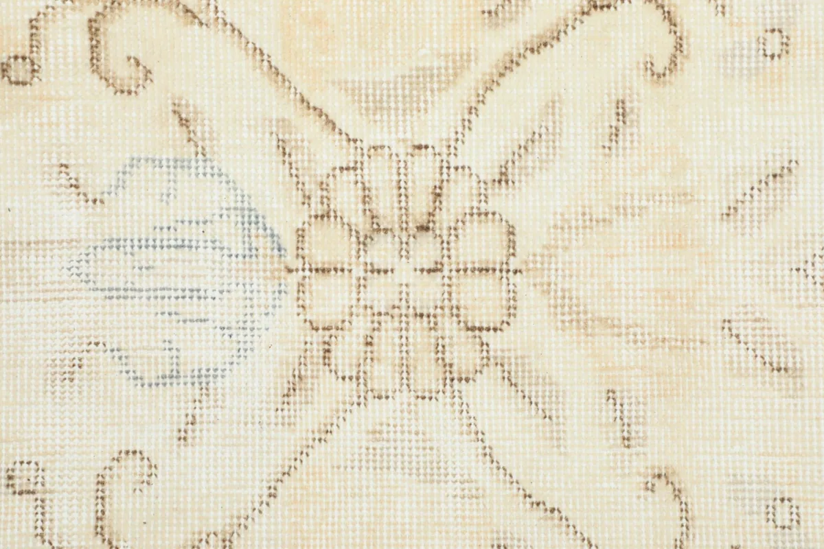 Very close detail of the hand-knotted wool pile and faded floral motif within the medallion