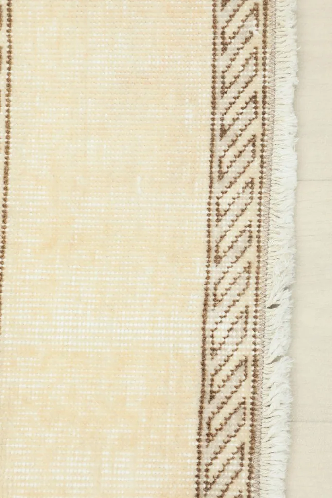 Close-up of the rug's cream fringe and a segment of the patterned border