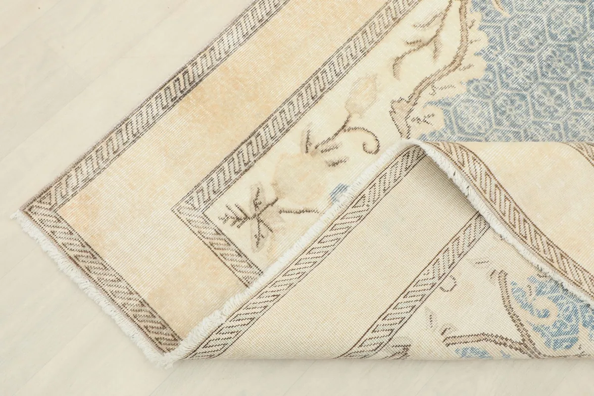 Corner of the rug folded back, revealing the reverse side and the hand-knotted cotton foundation