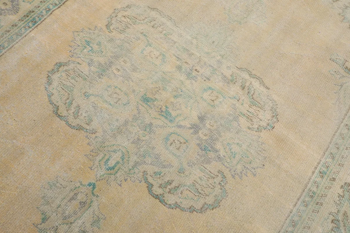 Detailed view of the central green medallion motif on the beige field of the vintage rug