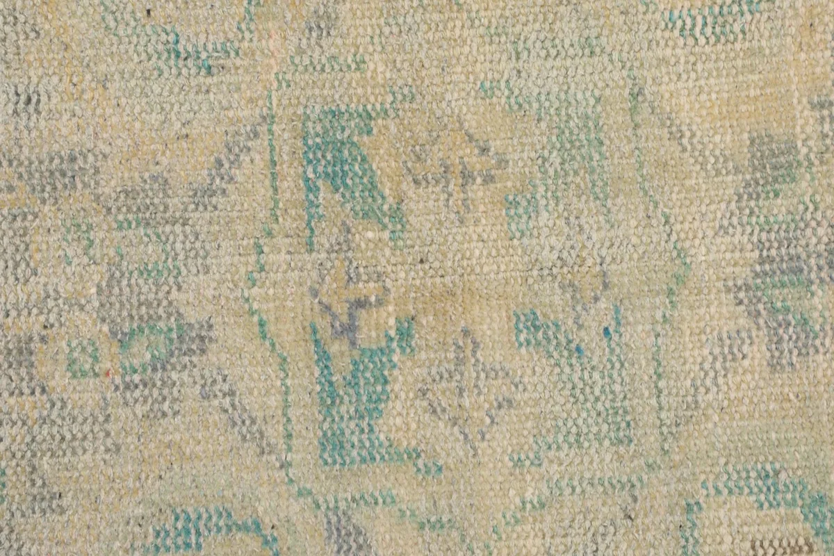 Close-up of the low wool pile, showing the texture and faded green and beige colors