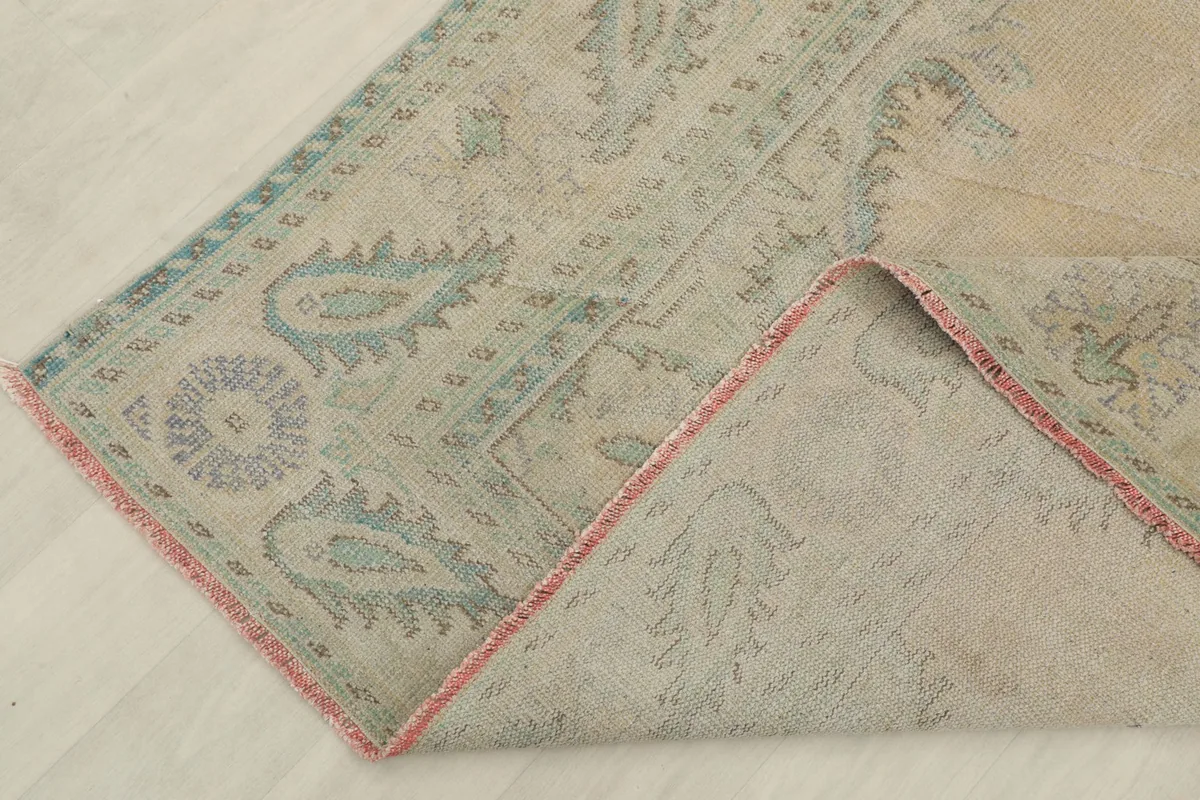 Corner of the vintage rug folded back, revealing the cotton foundation and hand-knotted construction