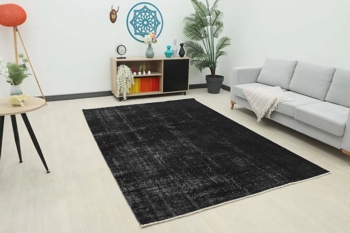 Vintage black and gray rug placed in a modern living room setting with a sofa and side table