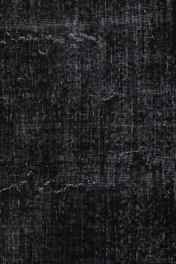Vertical detail shot emphasizing the texture and faded patterns within the black and gray rug
