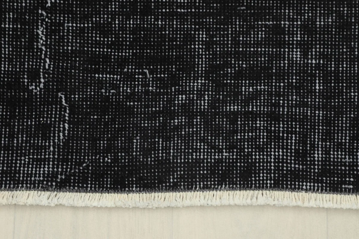 Close-up of the short, subtle fringes and the edge finish of the vintage black and gray rug