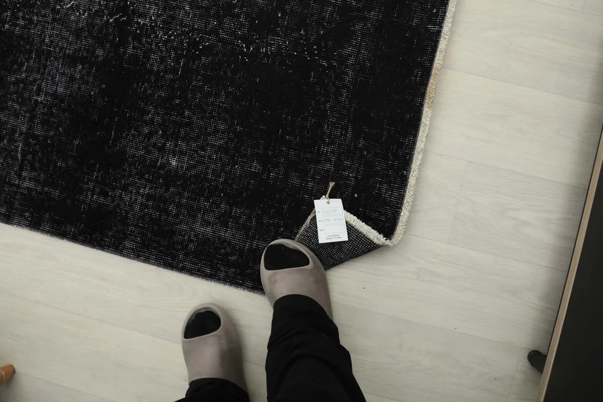 Overhead view with feet in slippers next to the rug, showing scale and a tag attached