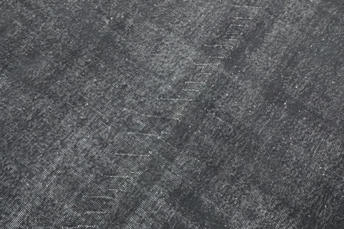 Detailed view of the rug's low pile and subtle linear patterns