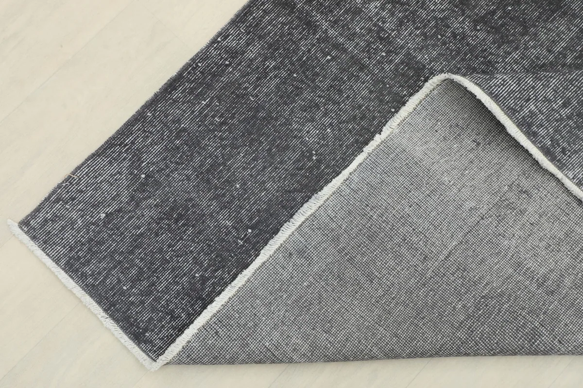 Corner view showing the reverse side of the rug, revealing the cotton foundation