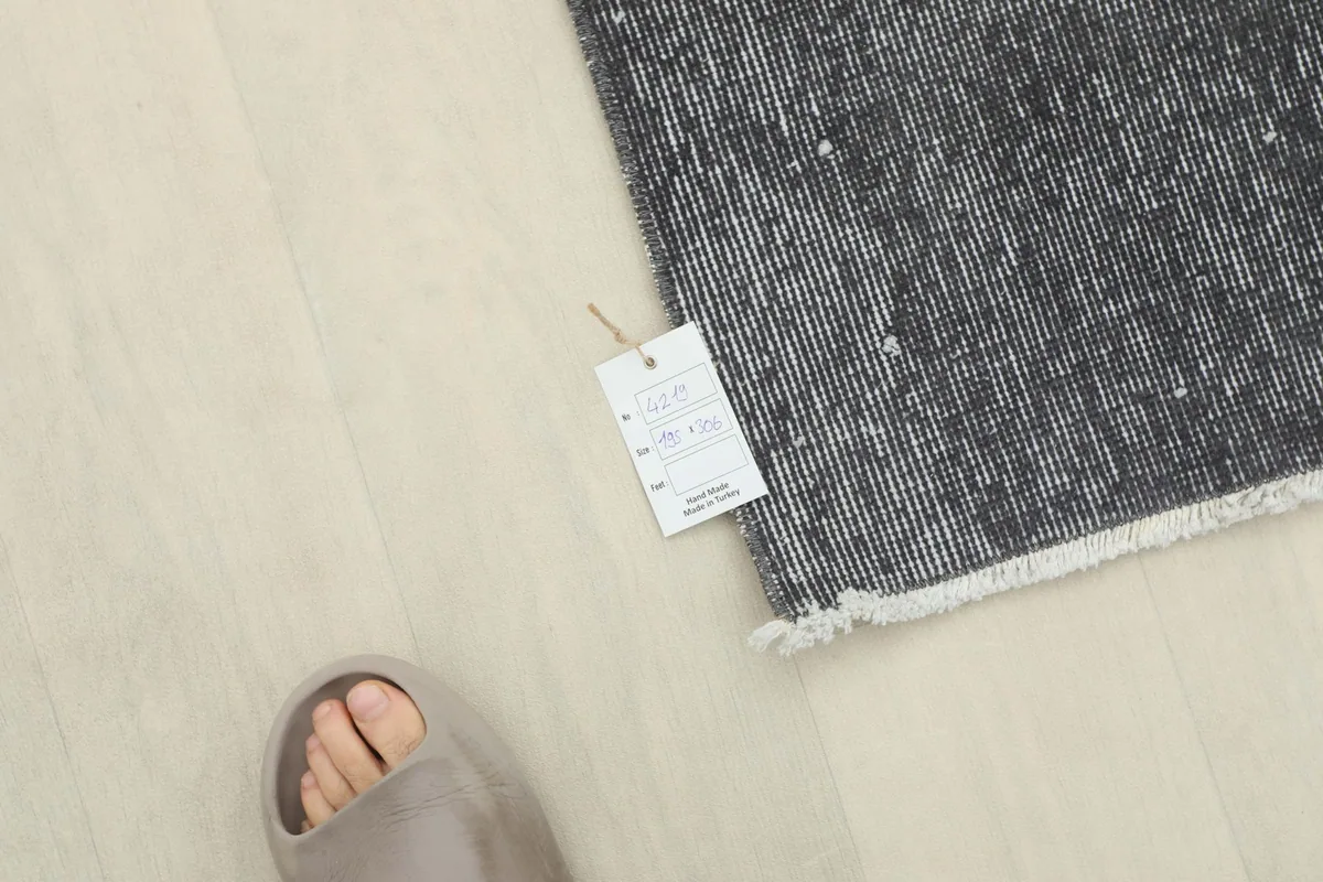 Overhead view showing the rug's corner with a product tag and a foot for scale