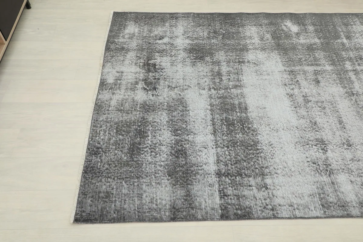 Close-up angled shot of the vintage rug's surface, revealing the blend of charcoal and gray tones.