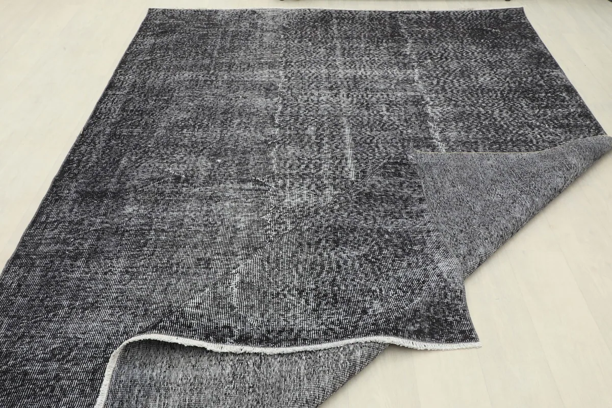 Corner of the rug folded back, displaying both the pile and the foundation.