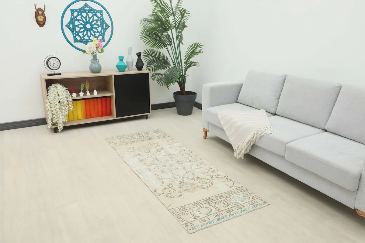 Beige and blue vintage runner rug placed in a modern living room setting with a light gray sofa.