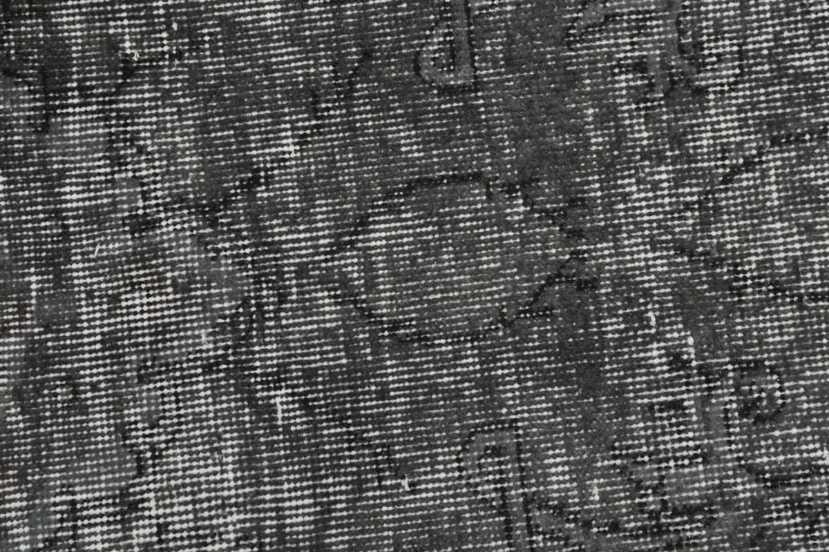 Close-up of the rug's surface, showing the hand-knotted wool pile and worn areas