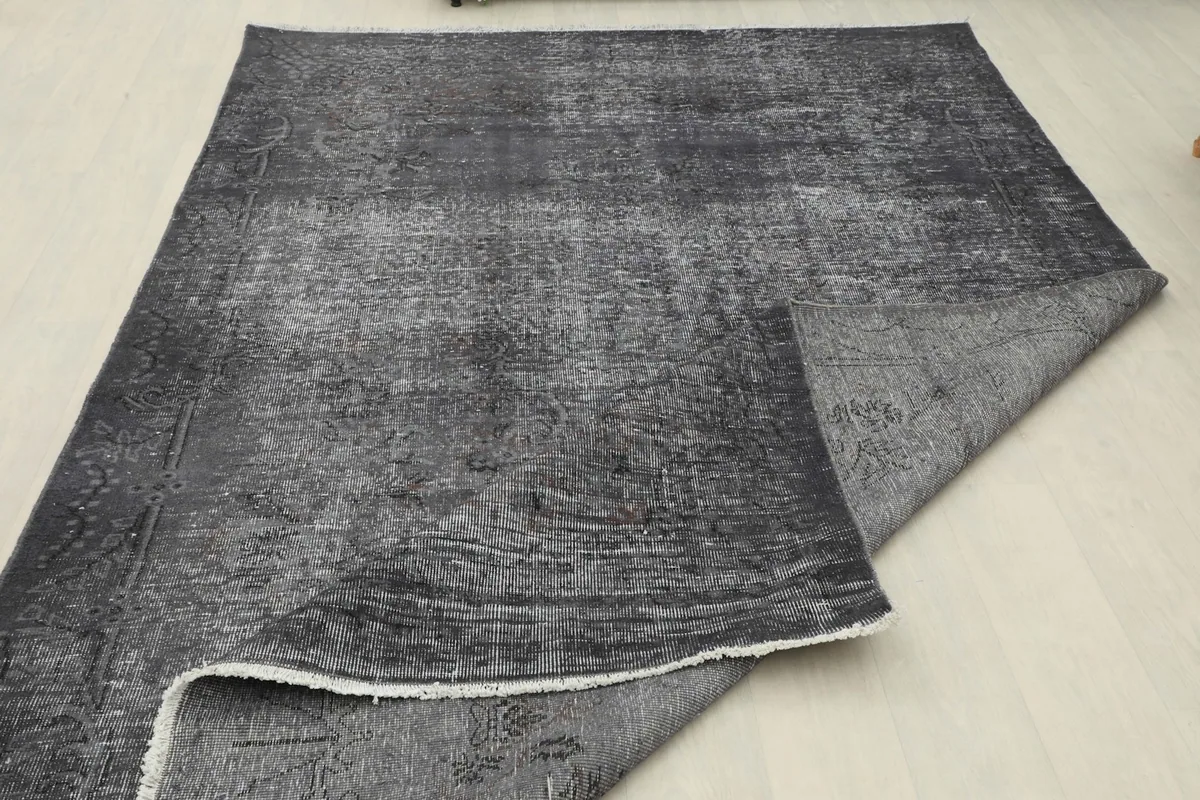 The charcoal rug partially folded, revealing the backside and pile texture