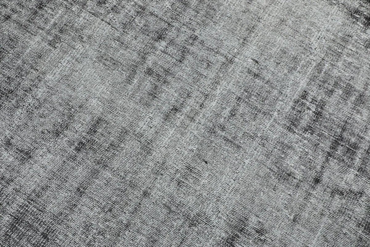 Detailed view of the distressed pattern and interwoven charcoal and gray fibers