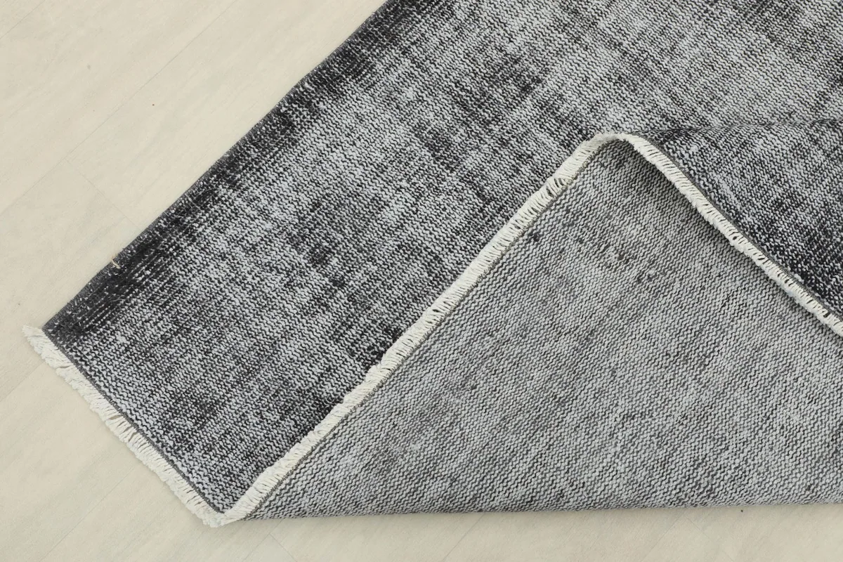 Corner of the rug folded to show the cotton foundation and the reverse side