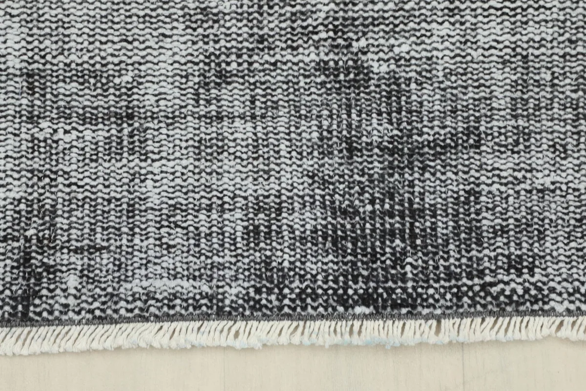 Detail of the rug's edge with short, light-colored fringes and the low pile