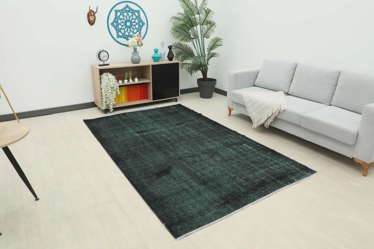 Vintage green and black rug placed in a modern living room setting with a light gray sofa.