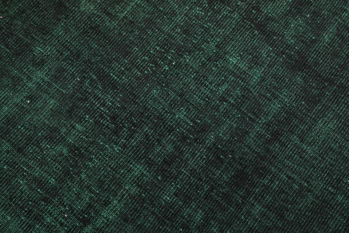 Detailed view of the wool pile, revealing the hand-knotted construction and subtle green and black threads.