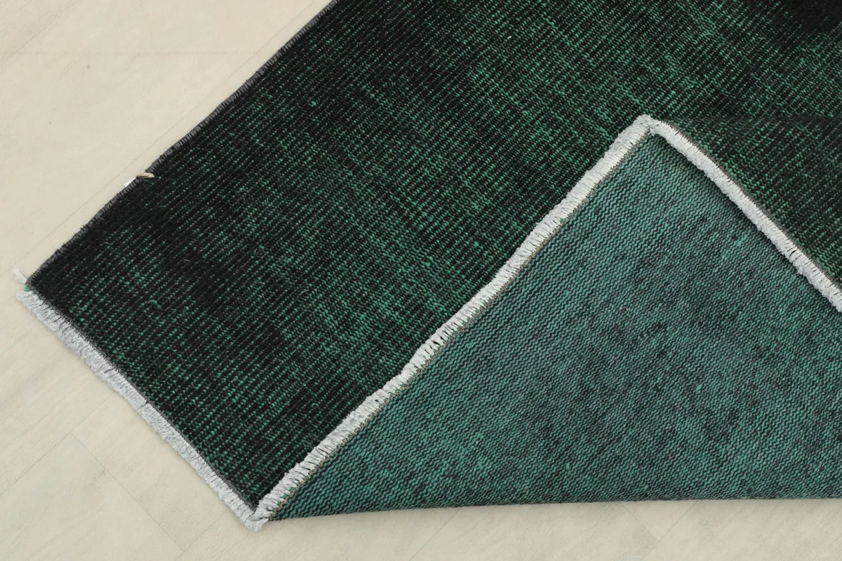 Close-up of the rug's folded corner, displaying the sturdy cotton foundation and the back of the wool pile.