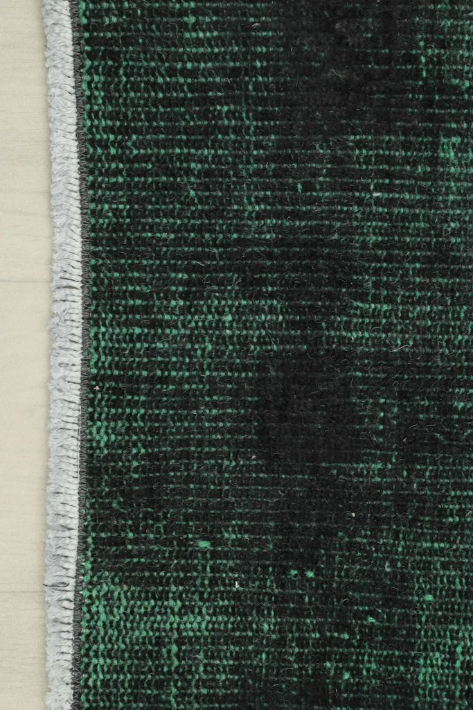 Edge of the rug with its short, natural cotton fringe and a glimpse of the hand-knotted structure.