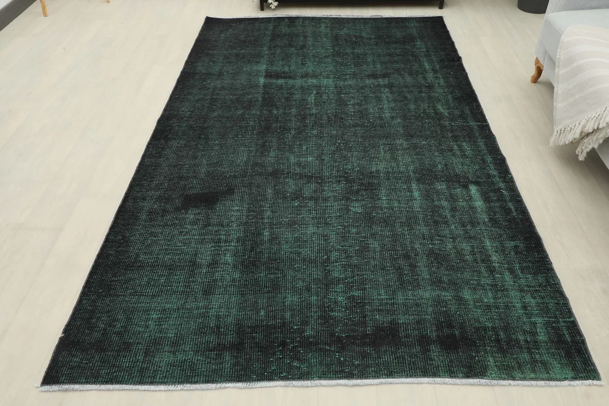 Full overhead view of the vintage green and black rug, highlighting its complete distressed appearance.