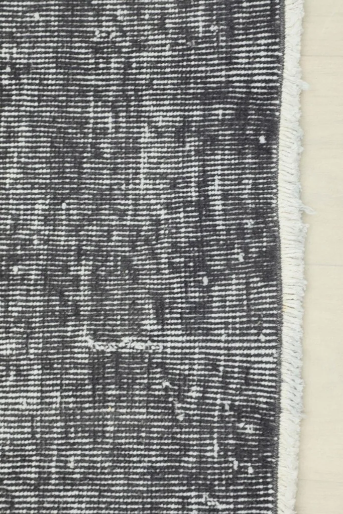 Detail of the rug's edge, showing the short, natural cotton fringe and the transition to the pile.