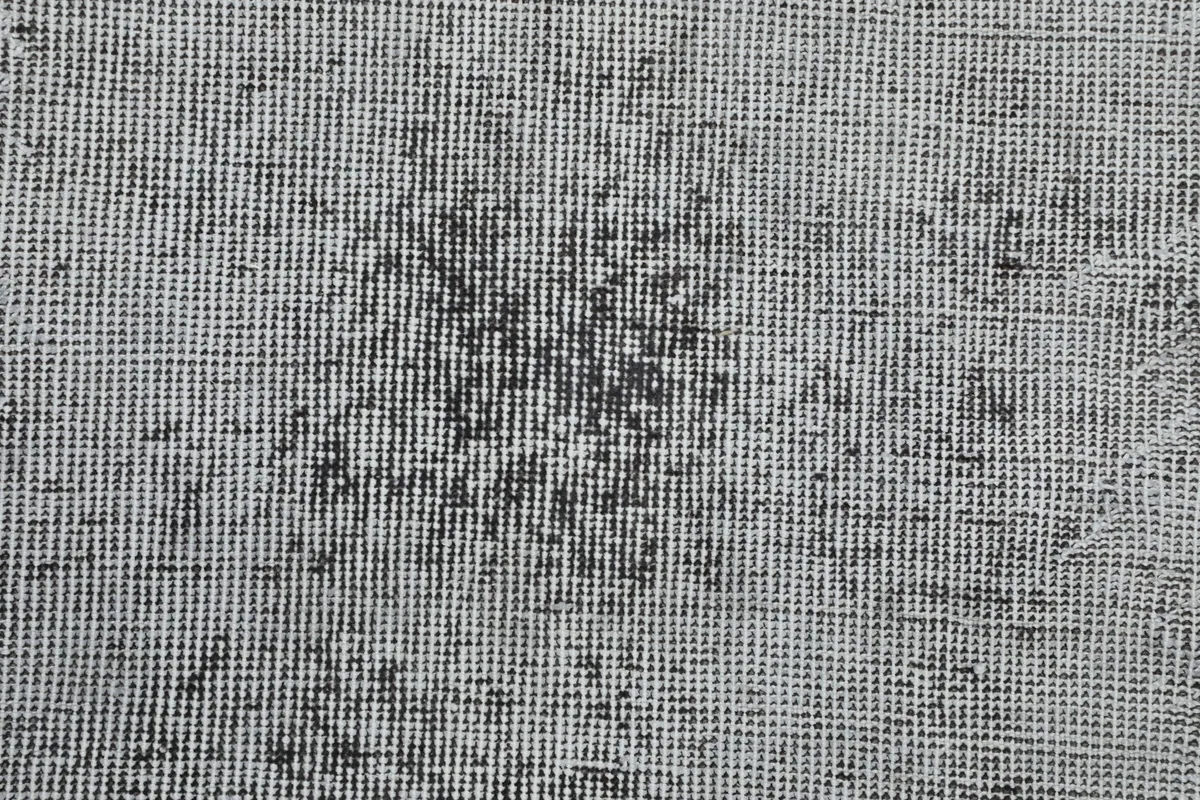 Close-up of the hand-knotted construction and the subtle geometric remnants in the gray pile