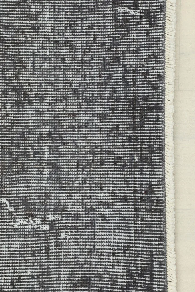 Detail of the rug's edge, showing the finished side and the short, light-colored fringe