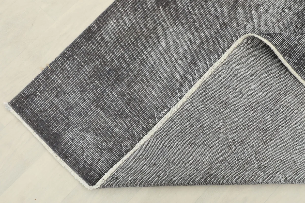 Corner of the rug folded to reveal the cotton foundation and the reverse side of the knotting