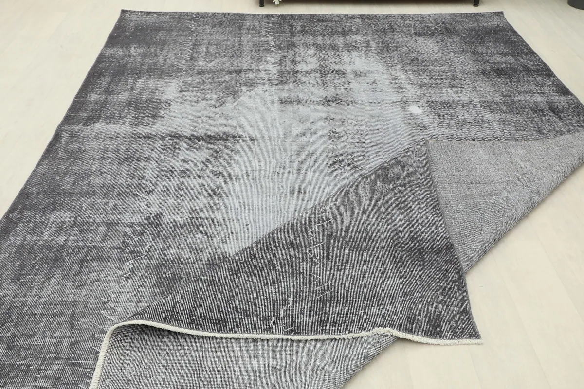 The large charcoal and gray rug partially folded, showing the flexibility and thickness