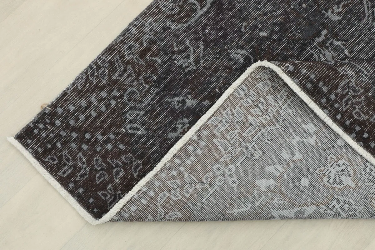 Corner of the rug folded to show the cotton foundation and the reverse side of the hand-knotting