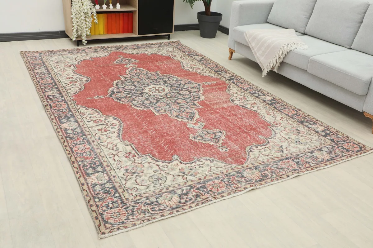 Angle view of the rust and navy vintage rug in a living space, showing its large scale.