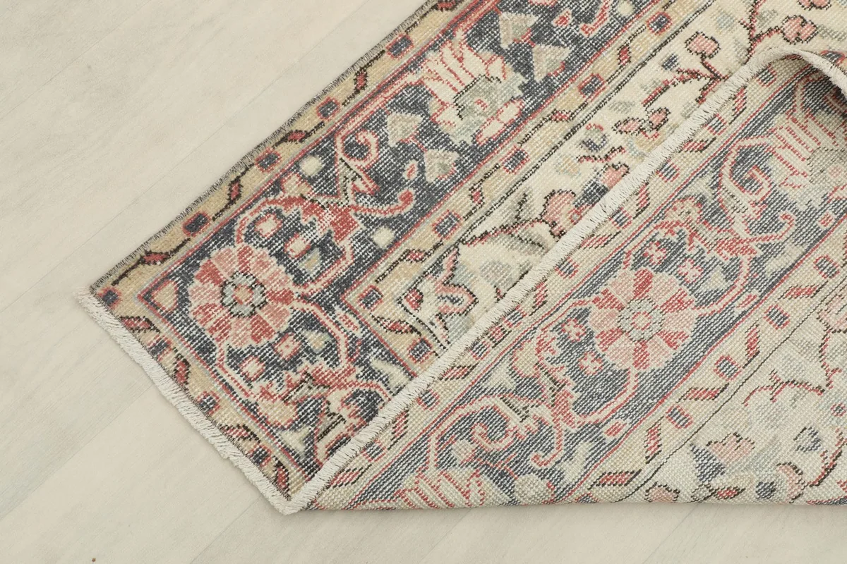 Corner of the rug folded back, revealing the reverse side of the hand-knotted wool on cotton foundation.