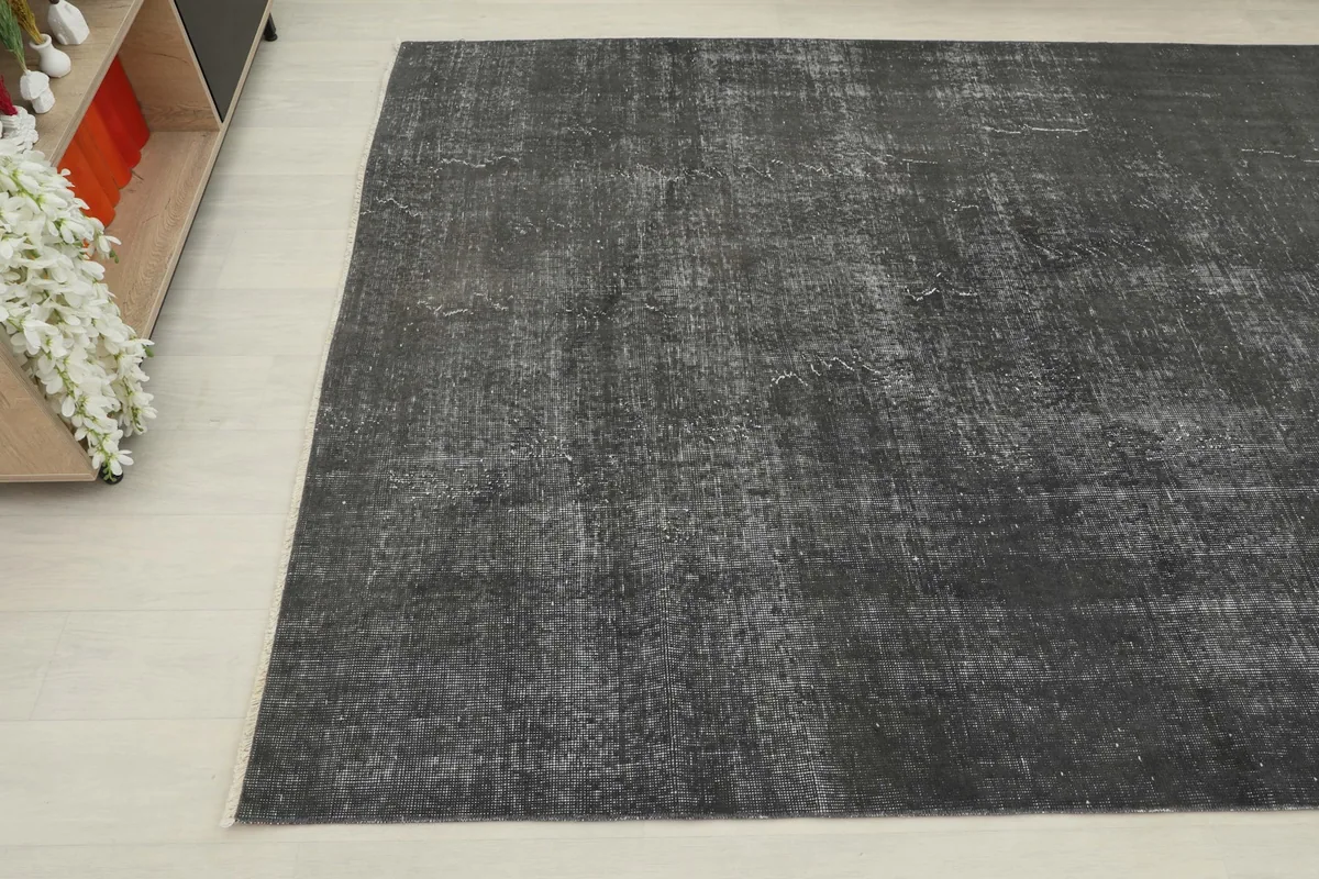 Corner view of the distressed charcoal rug, showing its muted gray tones and subtle wear