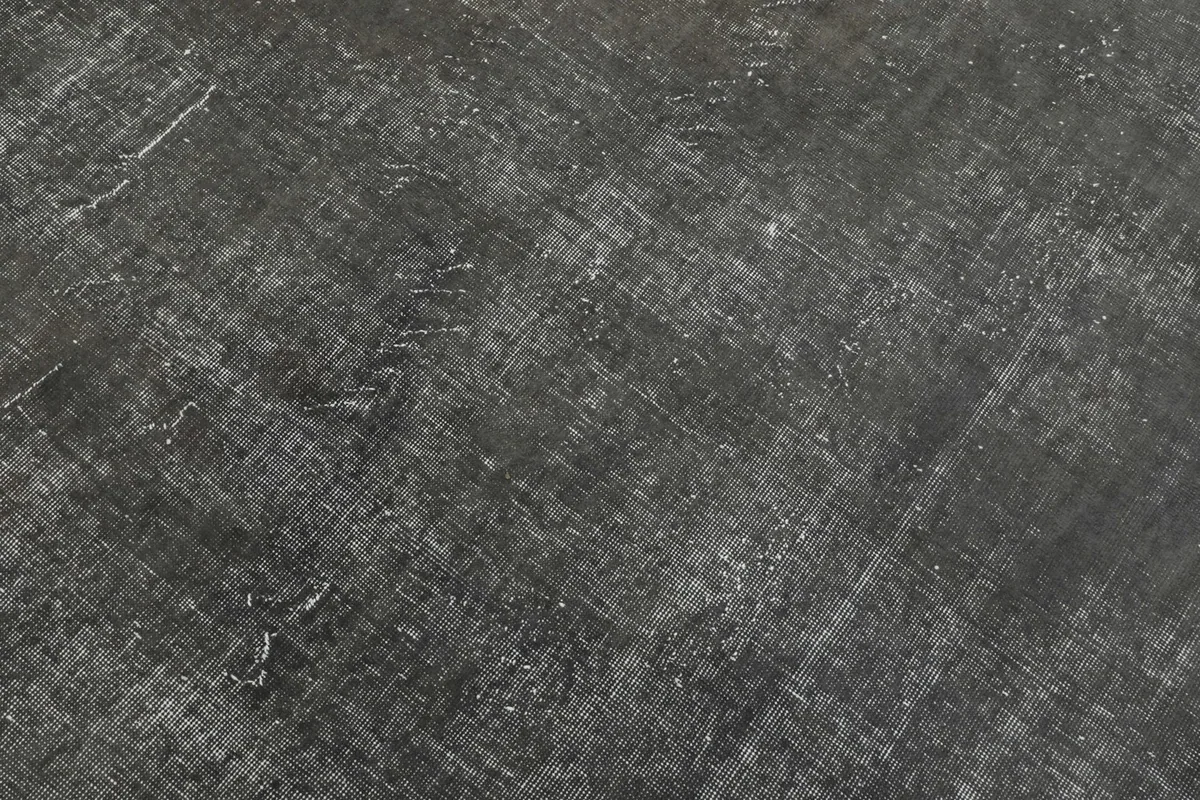 Close-up detail of the charcoal rug's surface, showing the low pile and textured finish