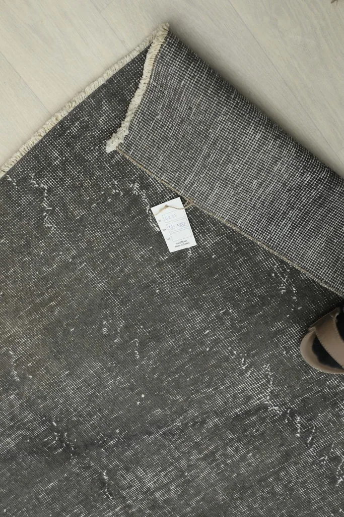 Overhead view of the folded rug corner with a size tag, showing the reverse side's weave