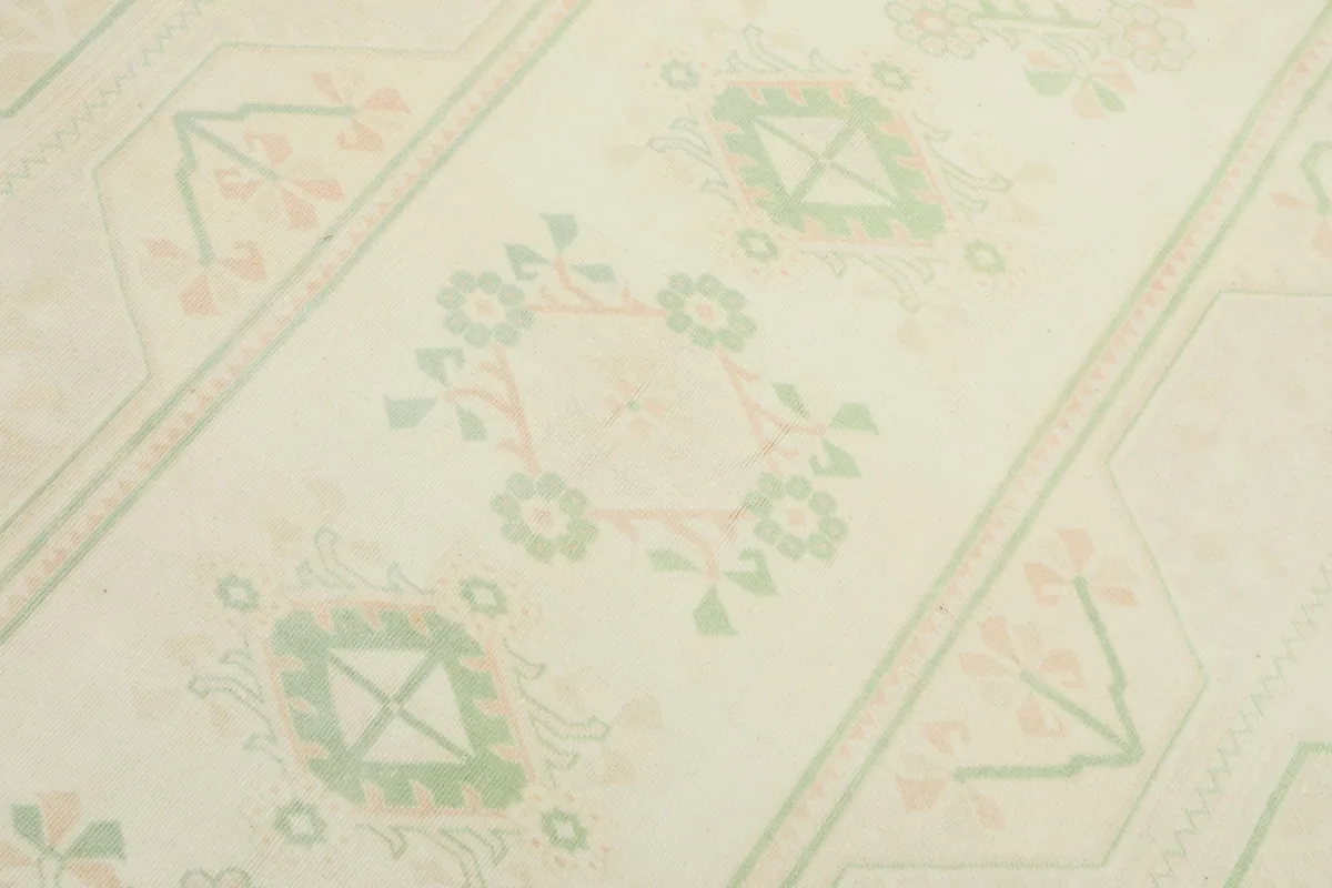 Close-up of the rug's central motifs, showcasing the blend of green geometric shapes and rose floral elements.