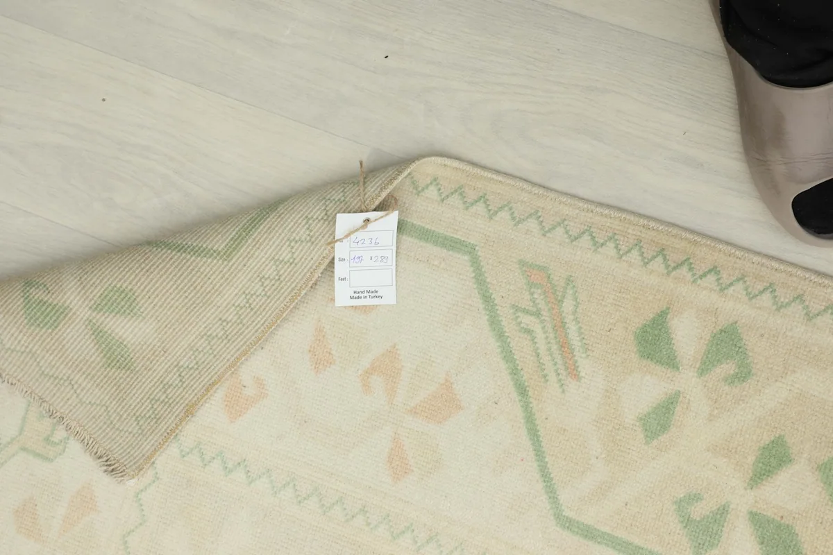 Corner of the rug with a product tag, showing the reverse side and hand-knotted texture.