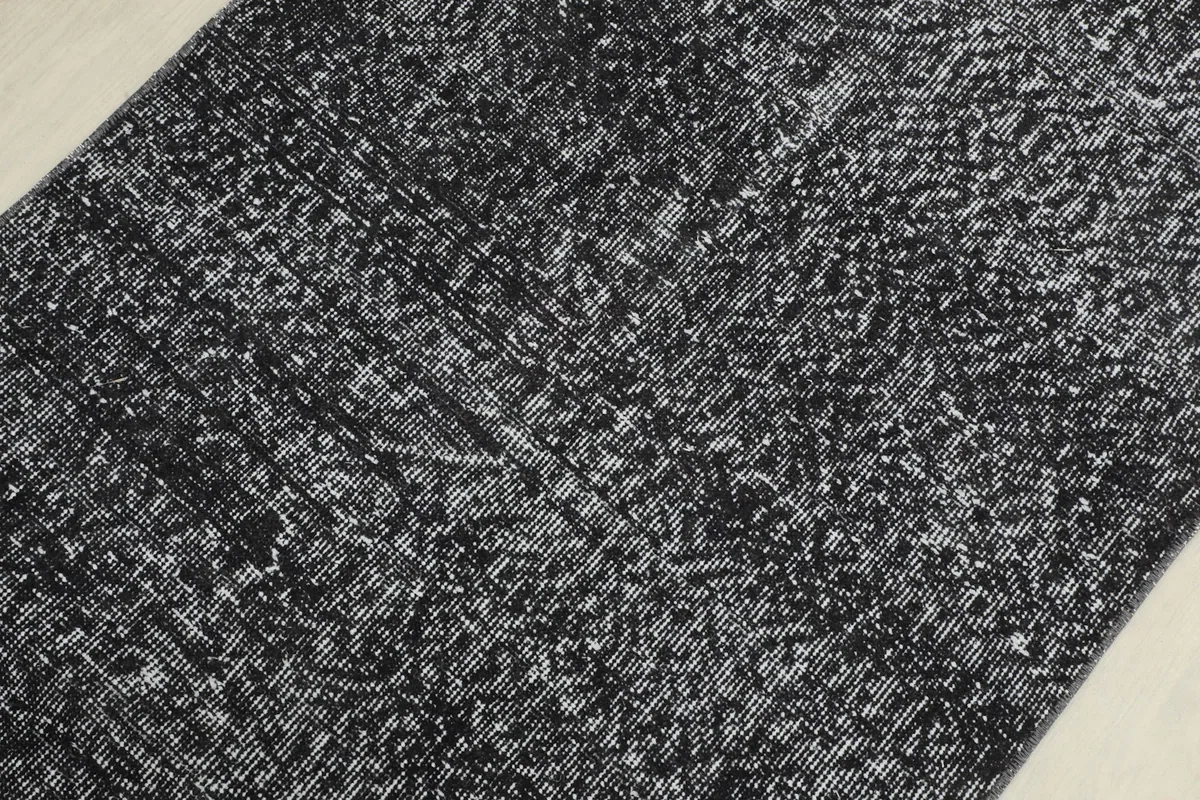 Detailed view of the rug's surface, focusing on the intricate, faded geometric motifs and texture.