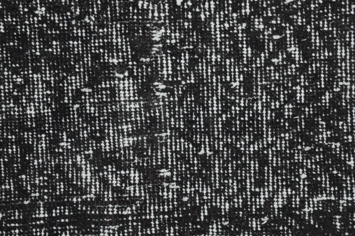 Close-up of the low wool pile, showing the hand-knotted construction and varied charcoal and gray threads.