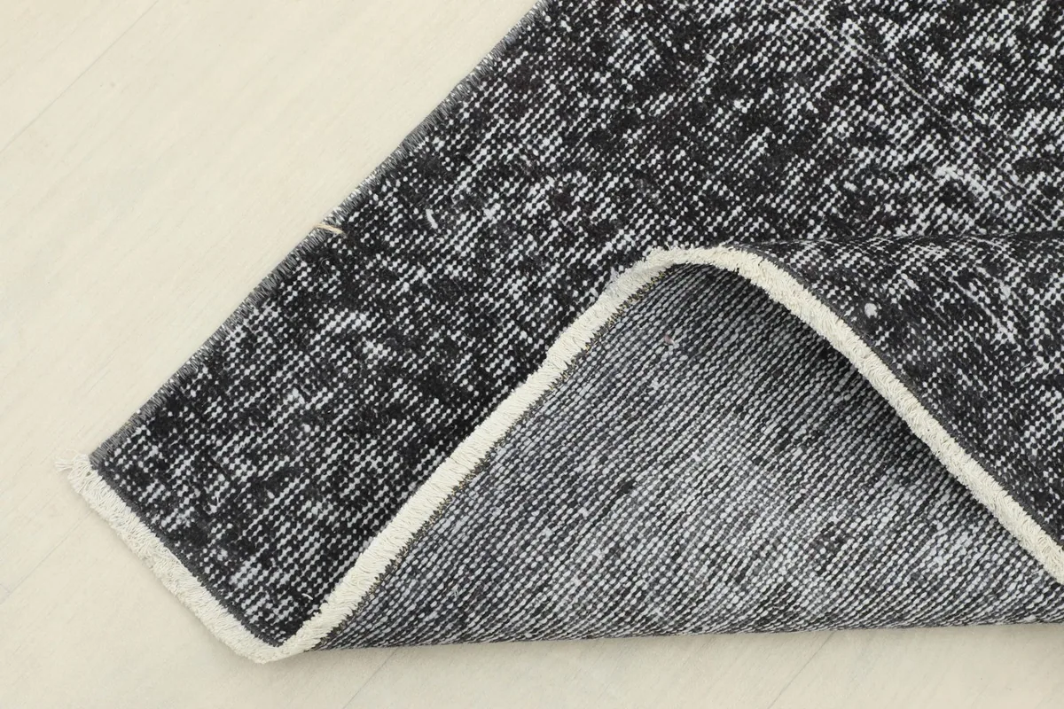 Corner of the rug folded back to reveal the cotton foundation and the reverse side of the hand-knotting.