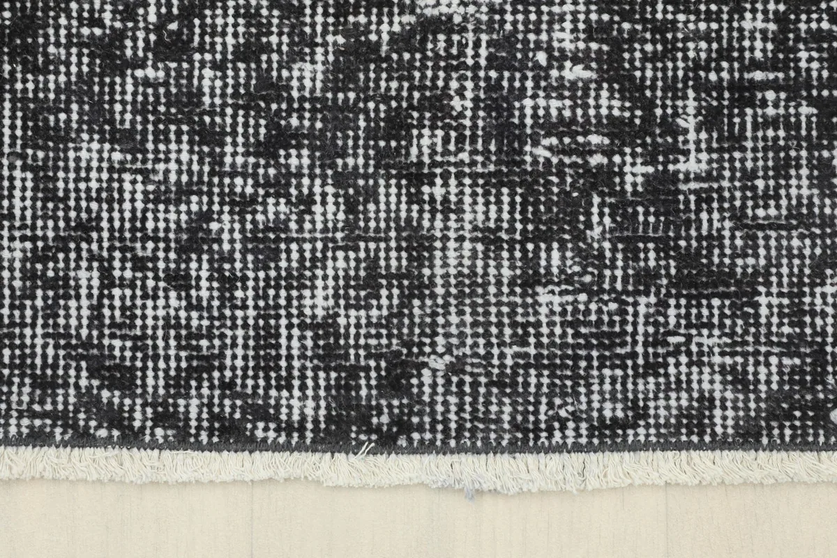 Detail of the rug's short, natural fringe and the edge where the pile meets the foundation.